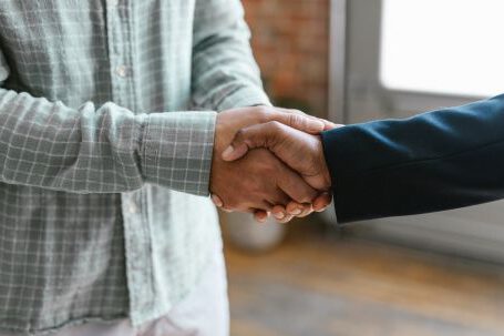 Investor's Criteria - A Person in Green Plaid Long Sleeve Shirt Shaking Hands with Person in Black Blazer